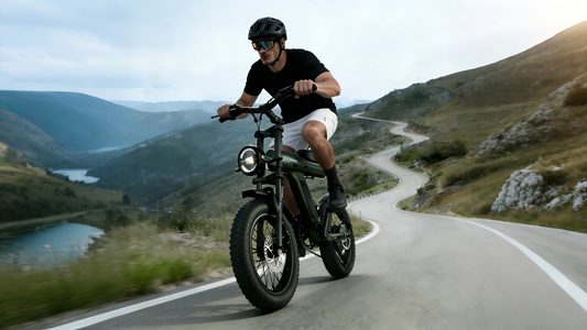 Dynamic motion shot of helmeted male rider cruising matte army green Jansno X90 retro fat tire e-bike on winding mountain valley highway beside alpine lakes.