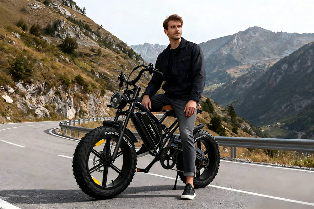 Mountain lifestyle shot of a man resting on matte black Jansno X50 retro fat tire electric bike on winding alpine mountain road.