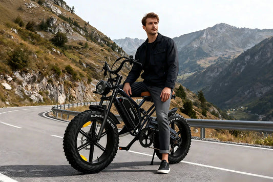 Mountain lifestyle shot of a man resting on matte black Jansno X50 retro fat tire electric bike on winding alpine mountain road.